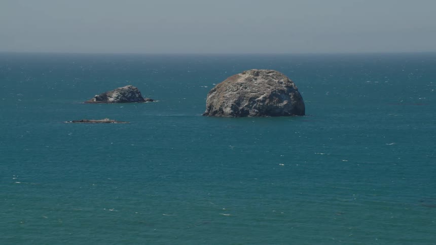Two large rocks in vibrant blue ocean water