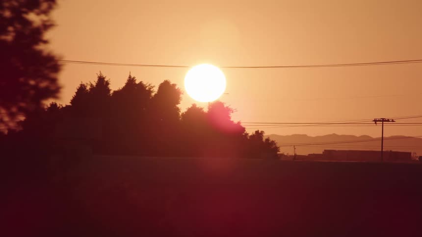 The sun sets behind a city