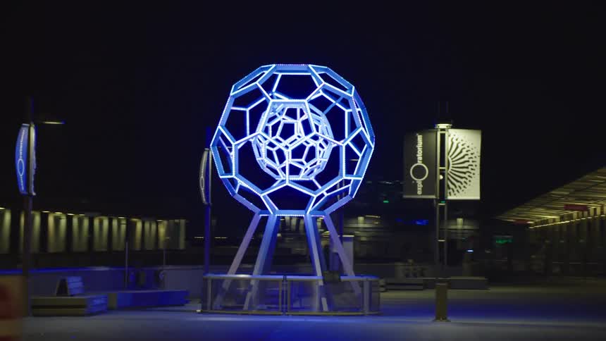 Modern art sculpture lights the night on a public park in city downtown