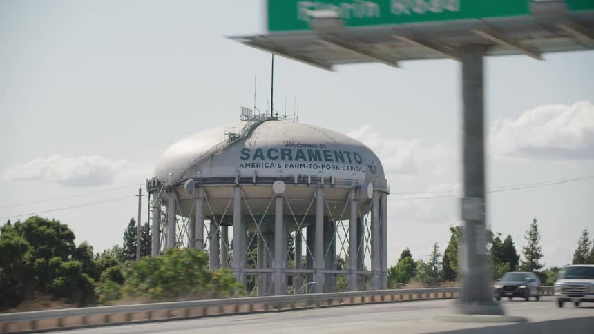A highway with a water tower with an american flag in the background