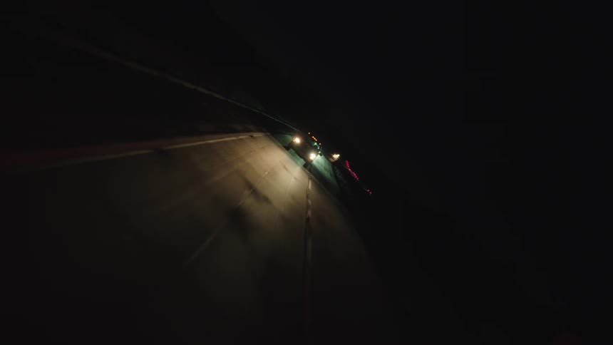 The vehicles travel together at night on the highway