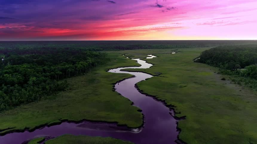 Birds eye view of winding river and vivid sunset