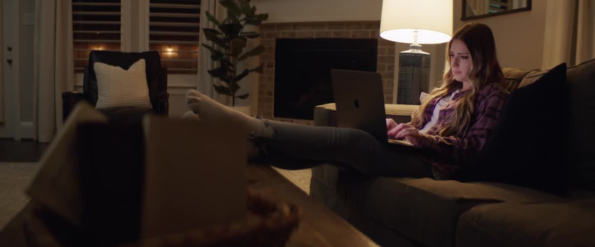A woman sitting on a couch typing on a laptop