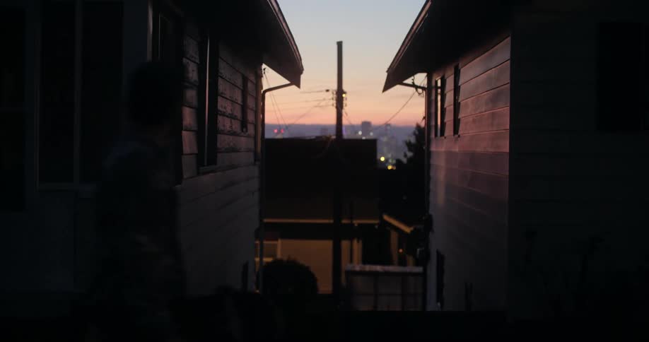 A person walking at sunset with houses in the background