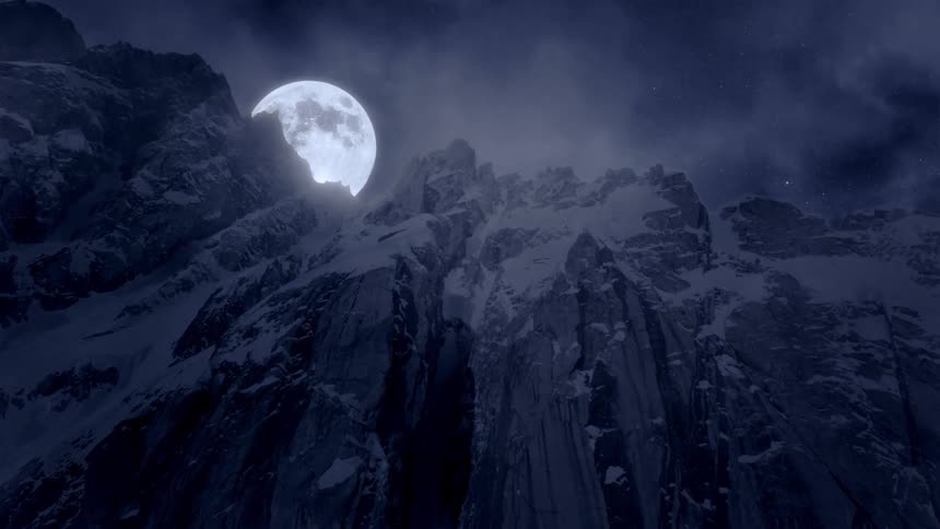 The moon peaking over a mountain top