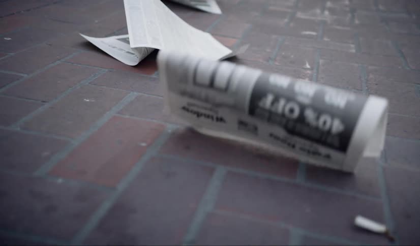 Newspaper pages blowing away on the ground in the city from wind