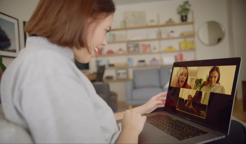Woman sitting on the couch makes a video call with her friends in the living room at home