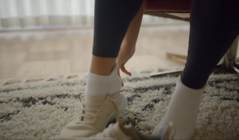 A female puts on running shoes