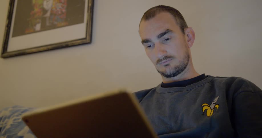 A man looks at a laptop while sitting down
