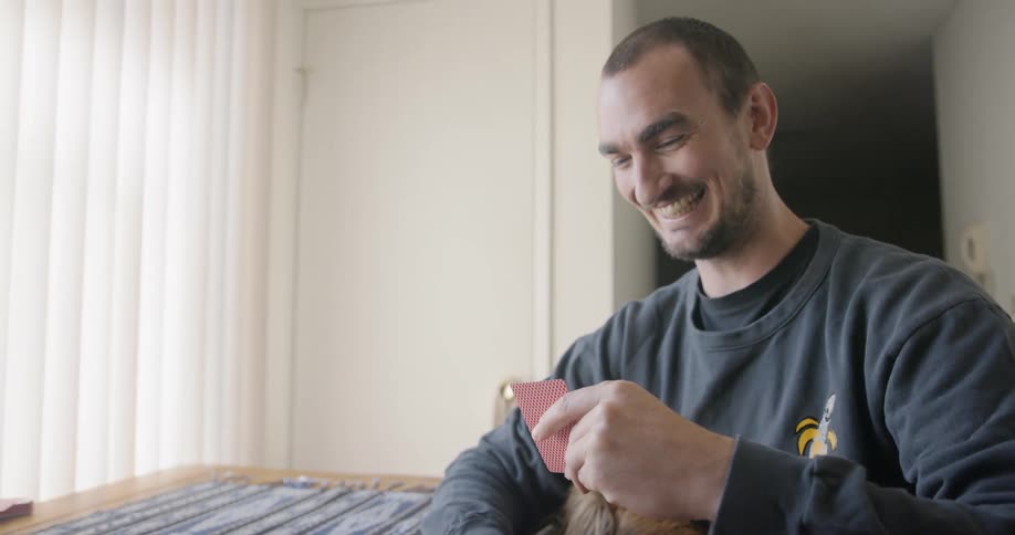 Couple play cards in living room with pet dog