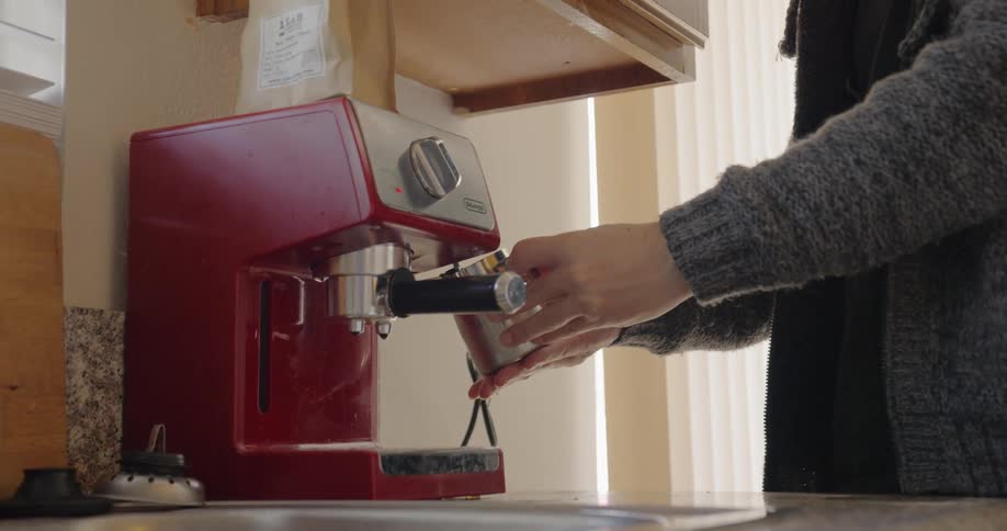 A person making a coffee using a coffee machine