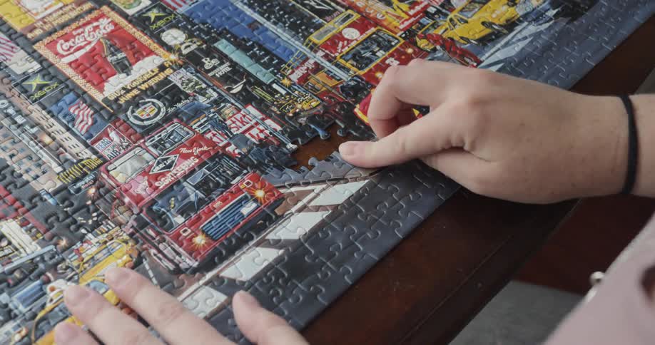 A woman puts a piece in a puzzle