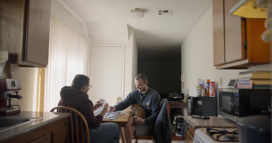 Couple play cards in kitchen table with dog