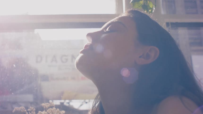 A woman stands in front of a window and looks up