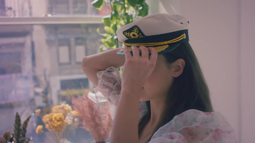 A woman puts a captains hat on