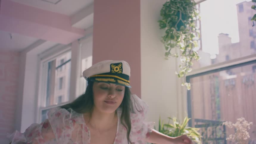 A female dances indoors while wearing a naval cap
