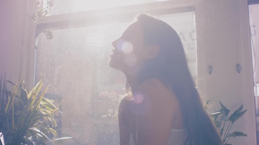 A female relaxing a the sun streams through her window
