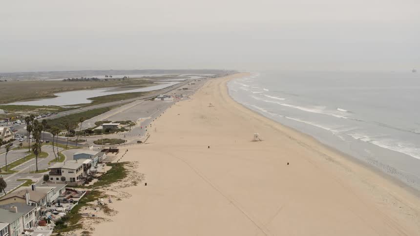 Aerial view of the ocean waves crashing against the beach on a cloudy day