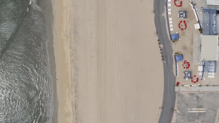 Waves crash on a beach near a road