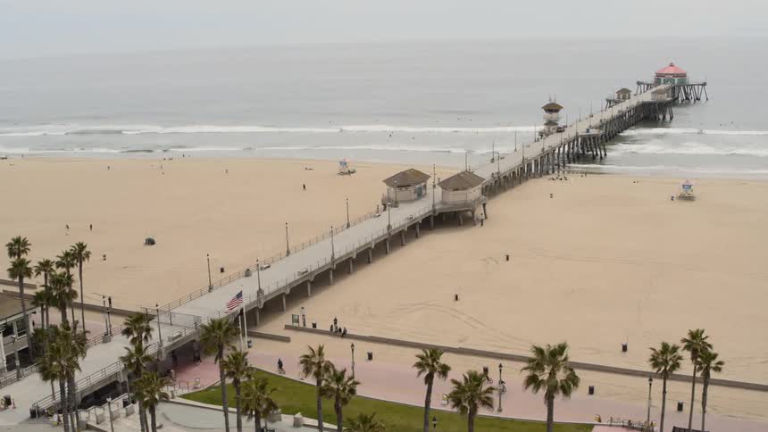 Aerial of a closed beach with a few people riding bikes on boardwalk