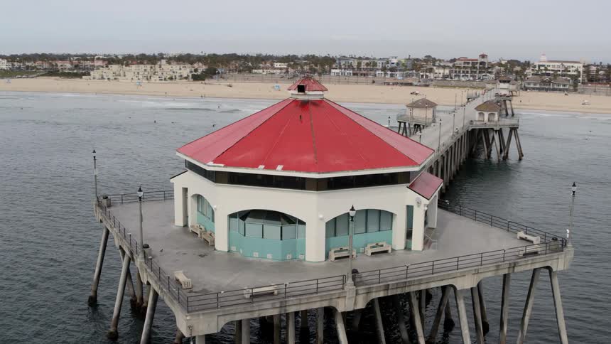 Aerial view of a round building at the end of the pier and sandy beach on a cloudy day