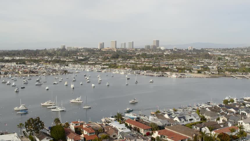 Boats fill the harbornear sprawling city with skyline and mountains toward the horizon