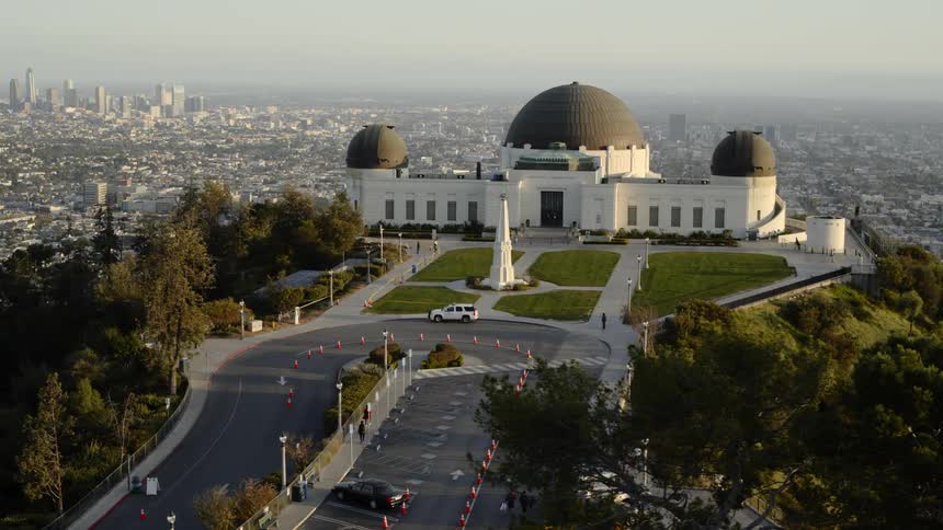 A large triple domed building on a hill by a city