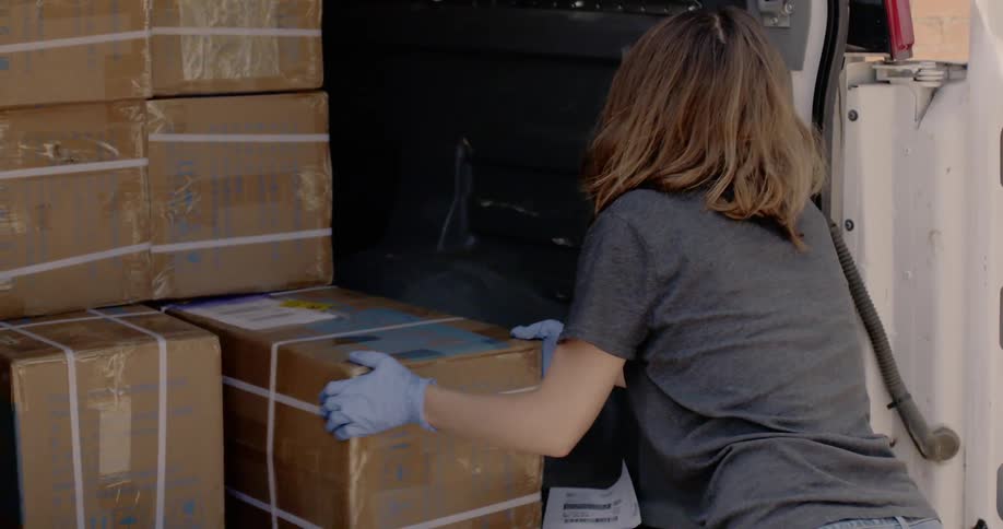 Woman takes a box to carry from the back of the van