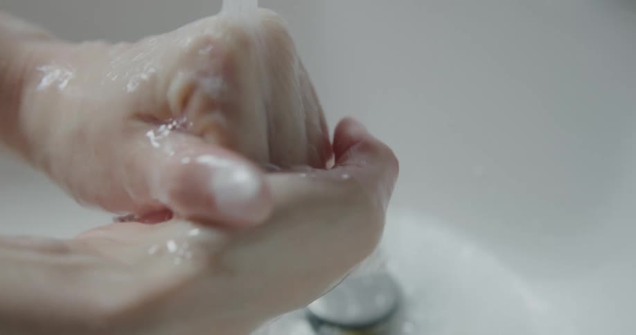A woman washes her hands in a sink