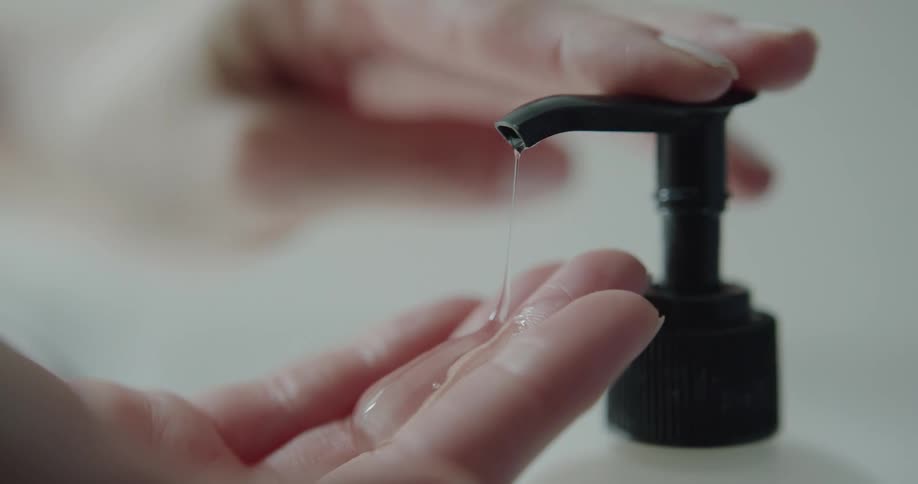 A person pushes down on a bottle pump to get soap on their hands