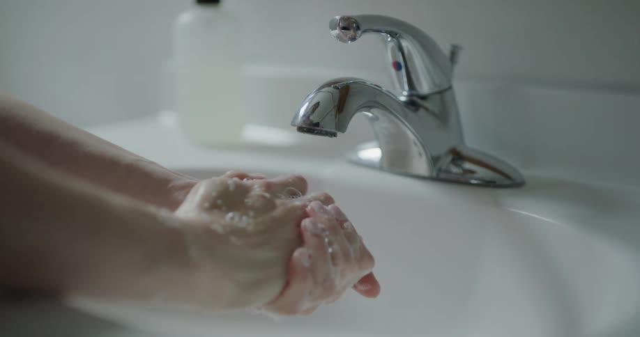 Woman washes her hands with soap in the bathroom