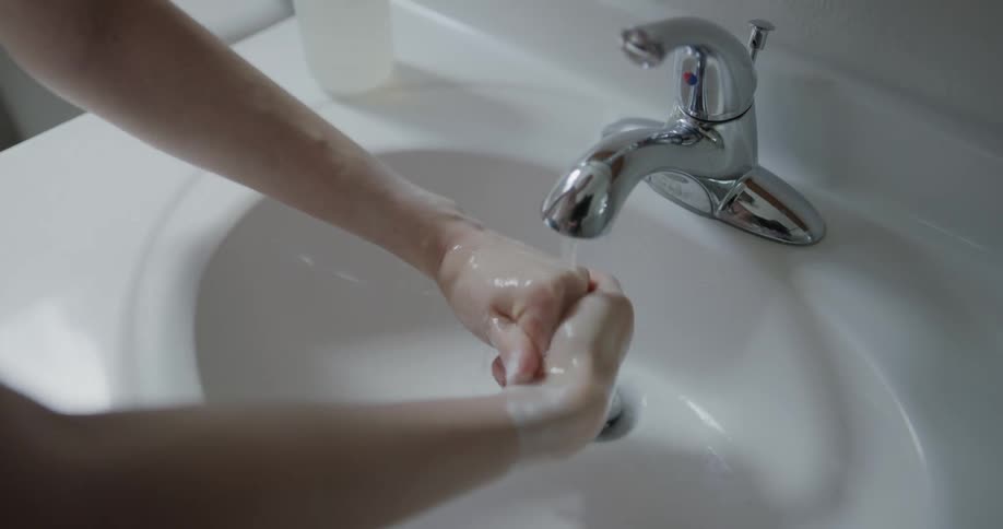 A person hands their hands in a bathroom sink