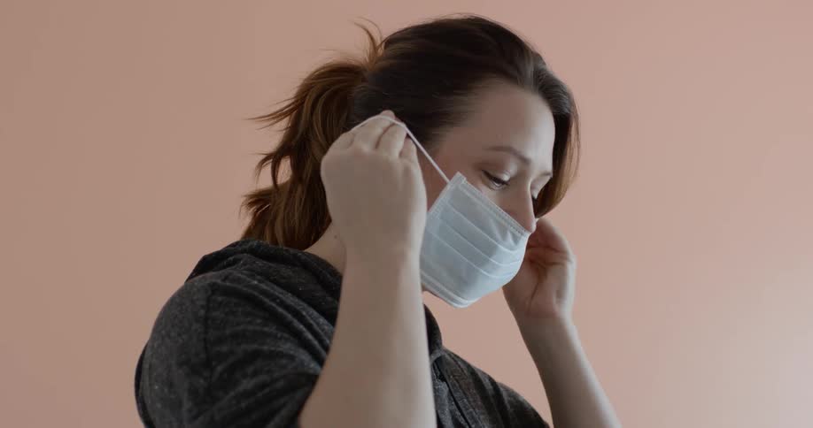 A smiling young woman putting on a face mask