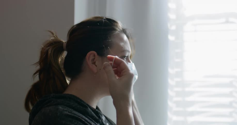 Woman takes off face mask inside room