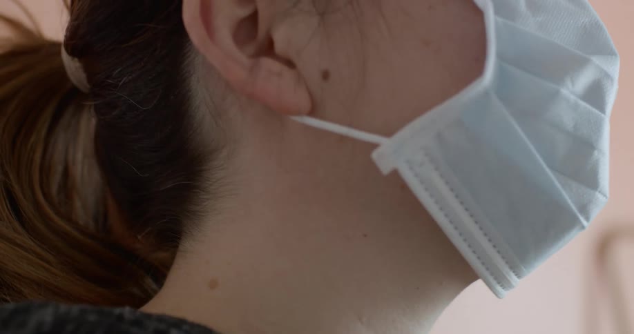 A woman adjusts her face mask