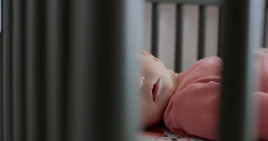 A baby lays quietly in a crib