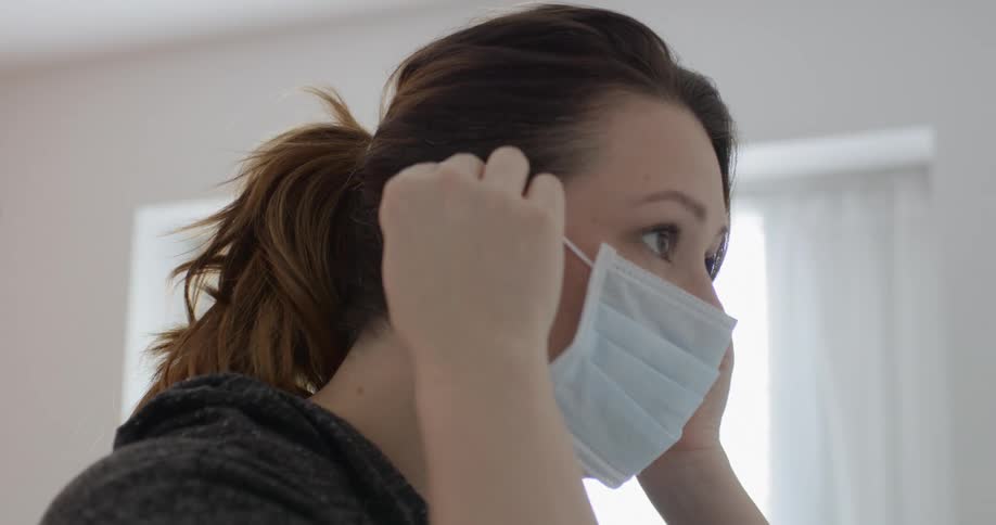 Woman puts on face mask in her room