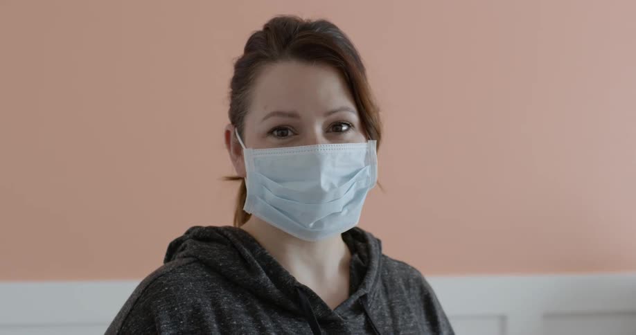 Woman wearing mask looks around in room