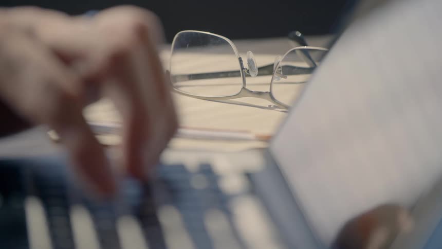A person typing on a laptop keyboard with one hand