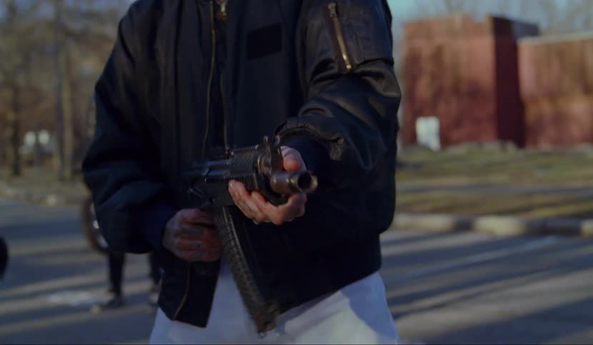 A teenager fires a gun in to the distance as another teen stands back and watches him