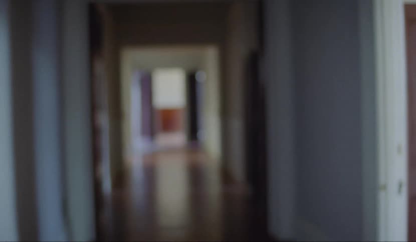 A teenager stumbles in to a hallway and nervously looks behind him