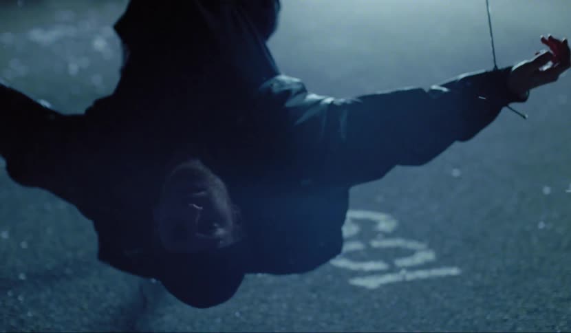 A man hanging upside down with a light in the background