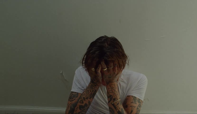 A man panicking while sitting against a wall
