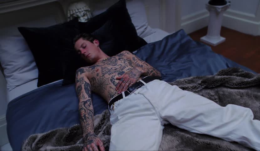 A man with lots of tattoos lays on a bed