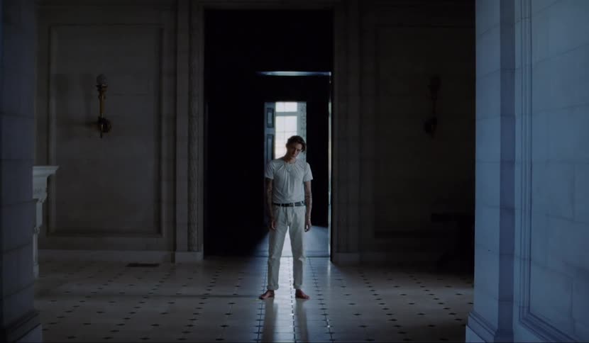 Man stands in ornate marble and white tile room just inside doorway staring