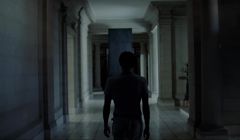 A man is walking through a dark hallway