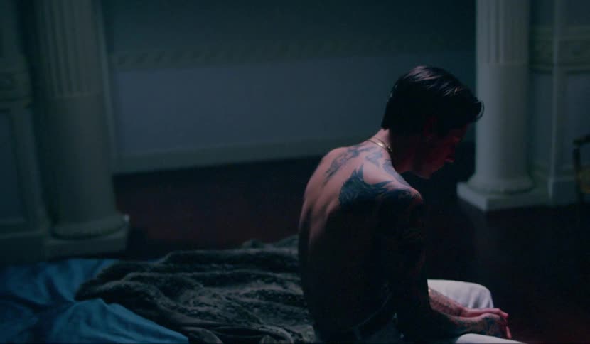 A man is sitting on a bed indoors