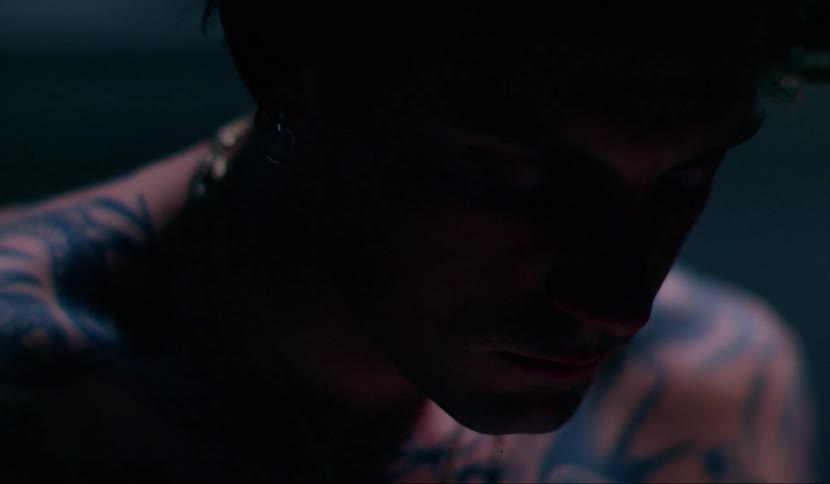 Close up of tattooed mans face sitting in dark room