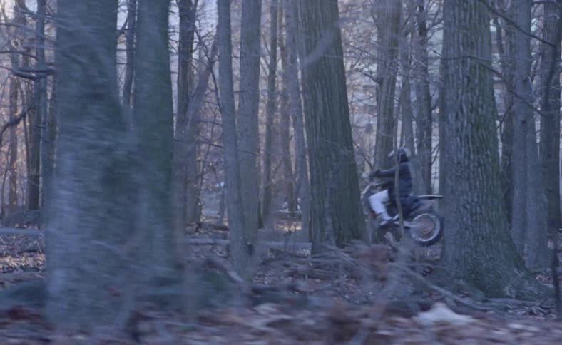 A woman drives a motorcycle down a path
