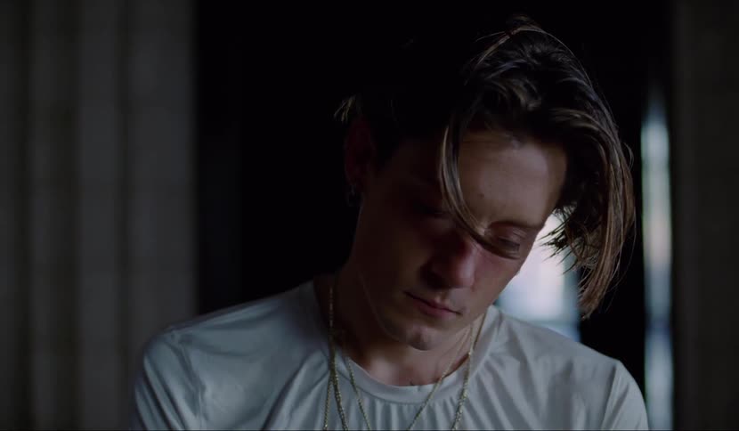 A young man stands in a hallway with his head cocked to the side